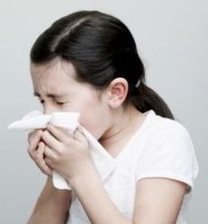 A girl sneezing into a tissue